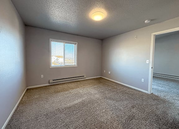 A room with a window and a carpeted floor.