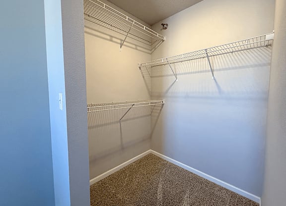 A walk-in closet with white walls and shelving.