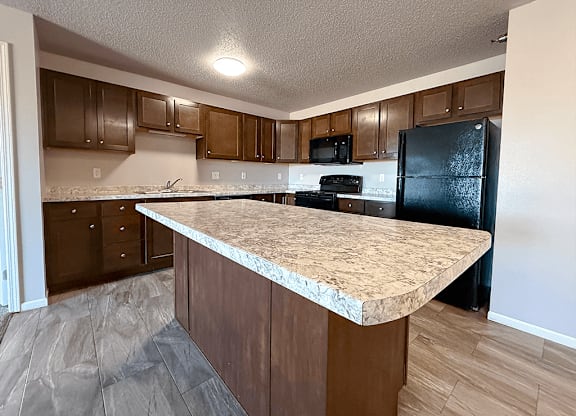 A kitchen with a granite countertop and wooden cabinets.