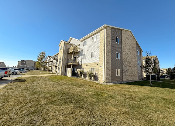 A large apartment building with a parking lot in front.