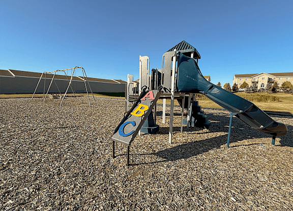 A playground with a green slide and a blue sky.