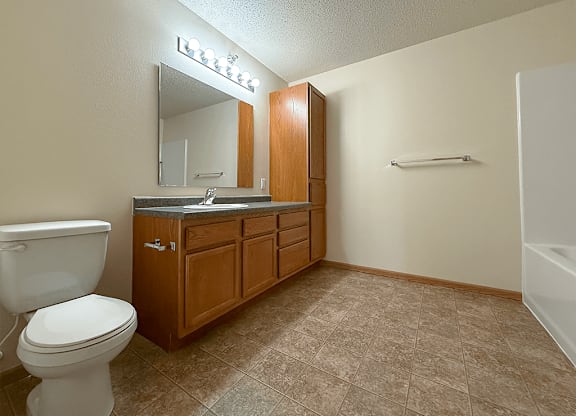 A bathroom with a toilet, sink, and mirror.