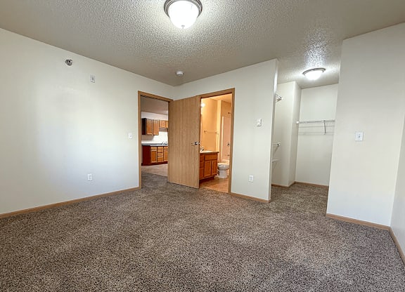 A sparsely furnished room with a carpeted floor and a doorway leading to another room.