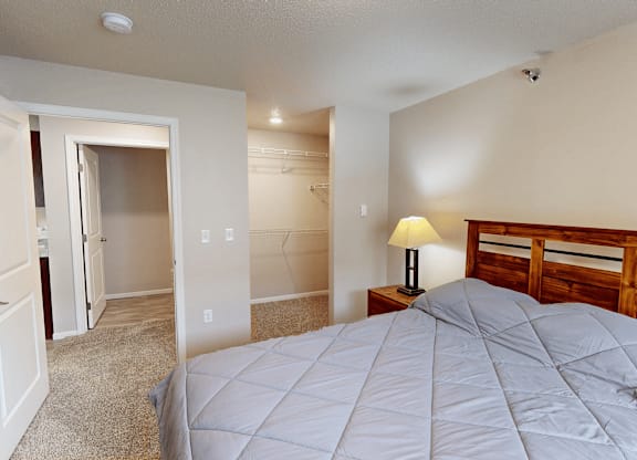 A bedroom with a bed, lamp, and two doors.