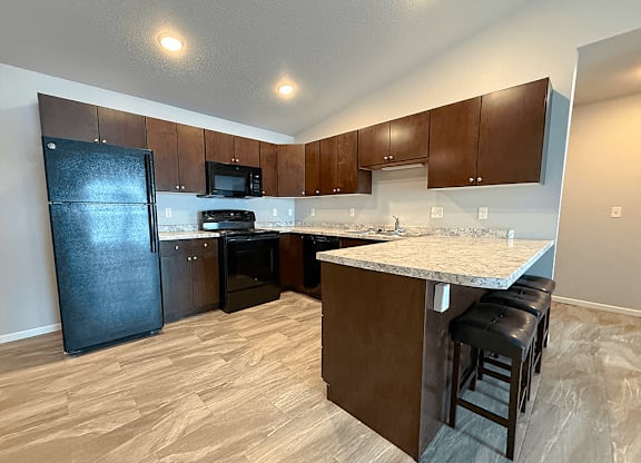 A kitchen with a black fridge, microwave, and oven.