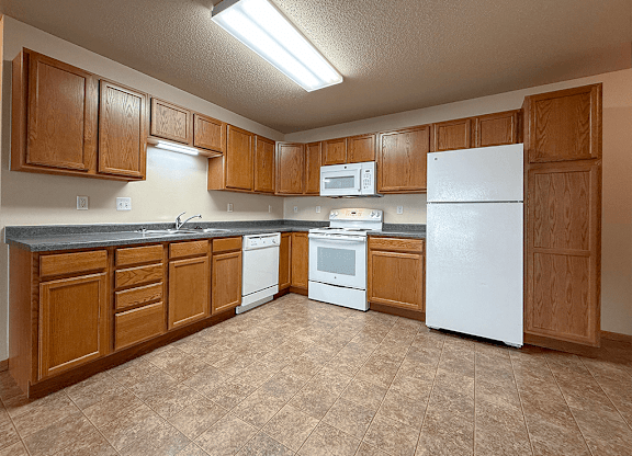 A kitchen with brown cabinets and white appliances.