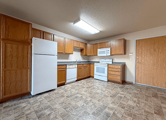 A kitchen with white appliances and wooden cabinets.