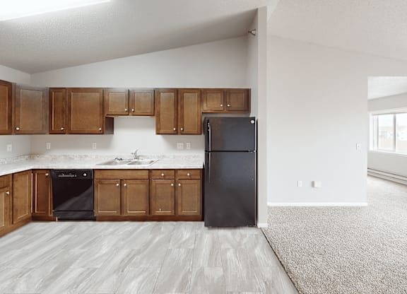 A kitchen with wooden cabinets and a black fridge.