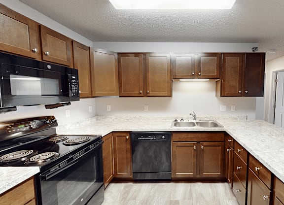 A kitchen with black appliances and wooden cabinets.