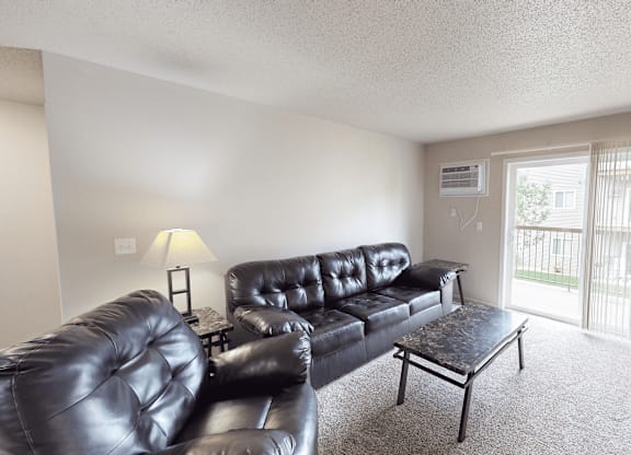 A living room with a black leather couch and a small table.