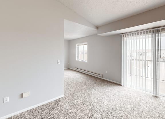 A spacious room with a sliding glass door leading to a balcony.