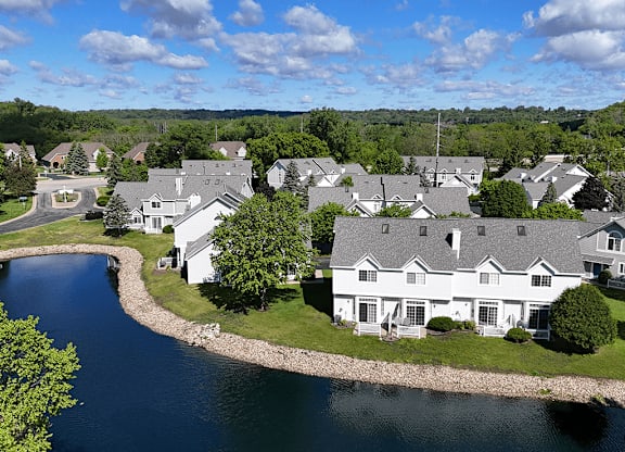 A large white house sits on the shore of a lake.
