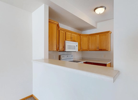 A kitchen with wooden cabinets and a white counter.