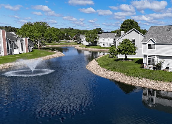 A fountain in the middle of a lake surrounded by houses.