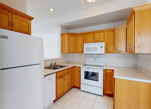 A kitchen with wooden cabinets and white appliances.