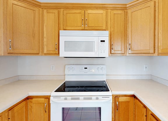 A kitchen with wooden cabinets and white appliances.