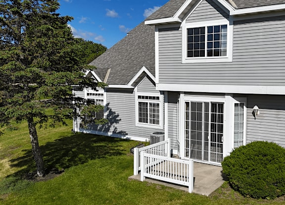 A house with a grey siding and a white fence.