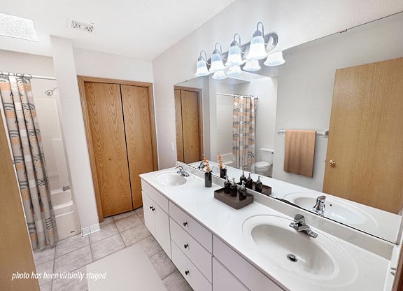 A bathroom with a white counter top and a white sink.