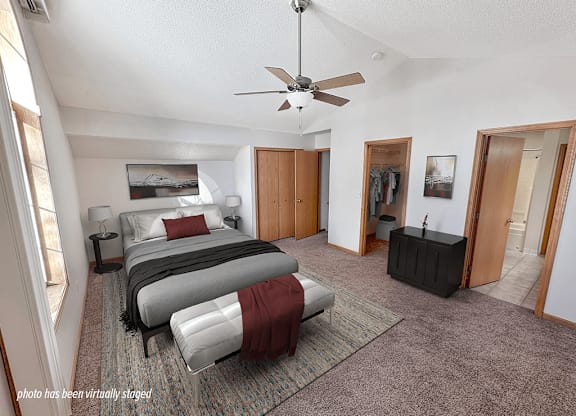 A bedroom with a bed, a dresser, and a ceiling fan.