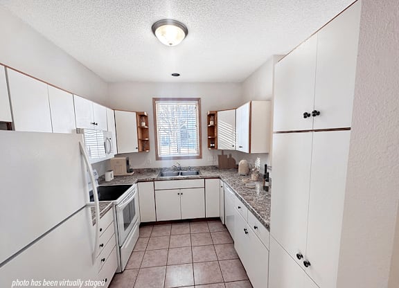 A kitchen with white cabinets and a tiled floor.