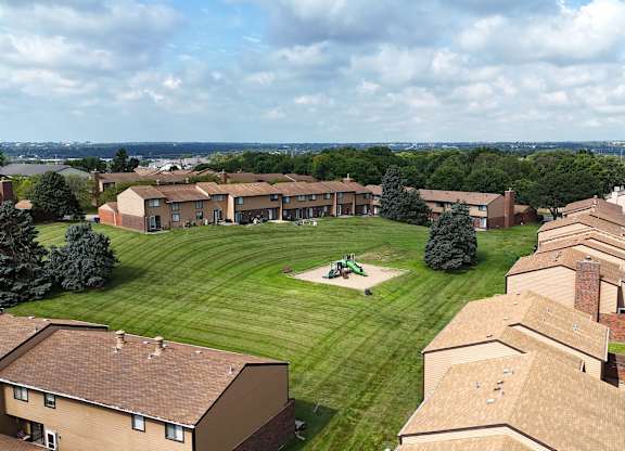 A view of a housing complex with a green lawn and a playground.