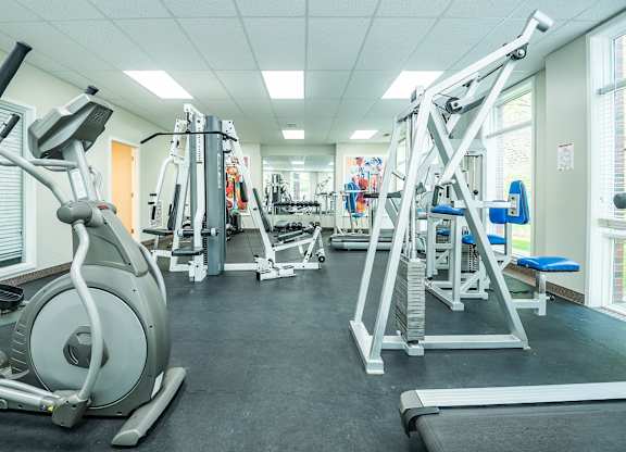 A gym with a variety of equipment including a treadmill, a stationary bike, and a weight bench.