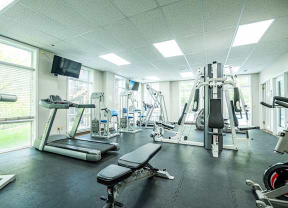 A gym with a variety of equipment including treadmills, weights, and exercise machines.