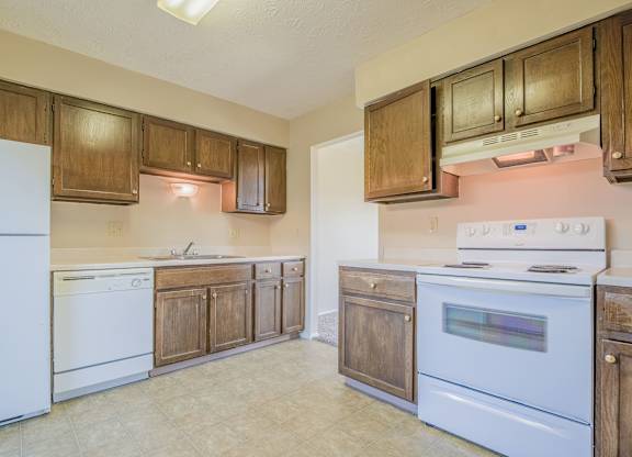 A kitchen with white appliances and wooden cabinets.