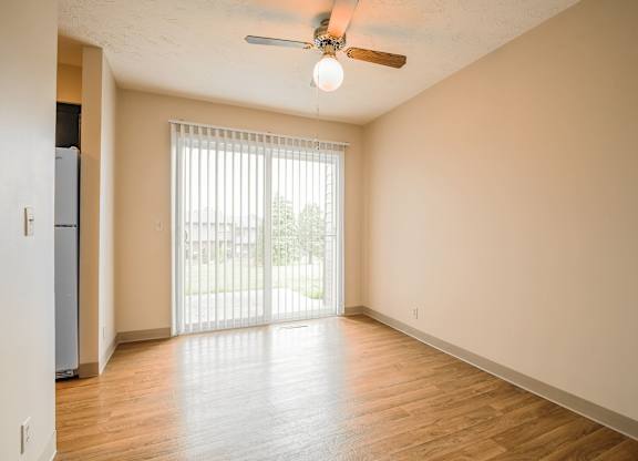 A room with a ceiling fan and sliding glass doors.