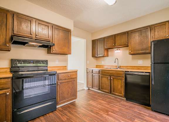A kitchen with black appliances and wooden cabinets.