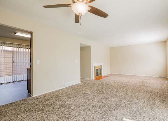 A room with a ceiling fan and carpeted floor.