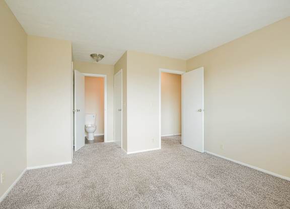 A room with carpeted floor and a toilet in the corner.