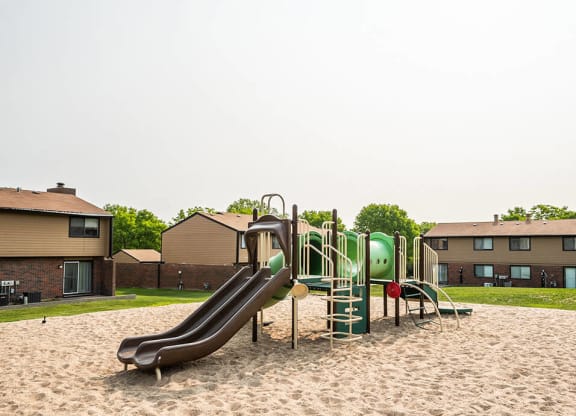 a playground with a slide in the middle of sand