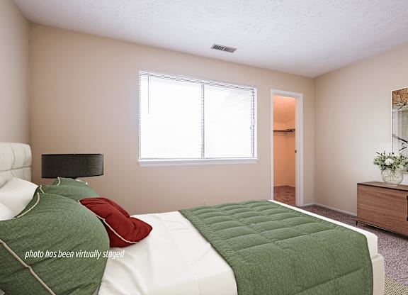 A bedroom with a bed, nightstand, and window.