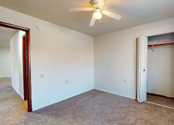 A room with a ceiling fan and carpeted floor.