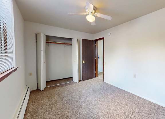 A room with a ceiling fan and carpeted floor.