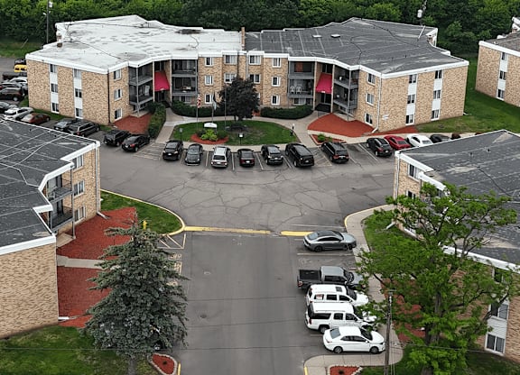 A parking lot in front of a building with cars parked.