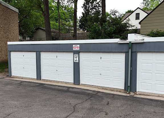 A row of garage doors with a sign on the first one.