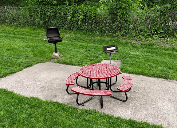 A red picnic table is in the middle of a concrete patio.