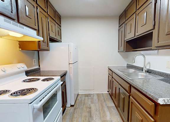 A kitchen with a white stove and brown cabinets.
