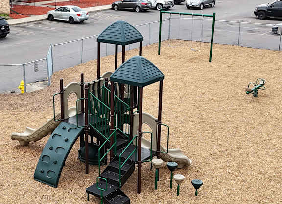 A playground with a green slide and a green roofed structure.