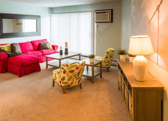 a living room with a red couch and yellow and pink chairs
