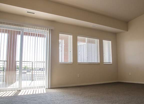 an empty room with a sliding glass door and four windows
