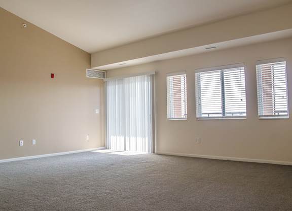 an empty room with a sliding glass door and three windows