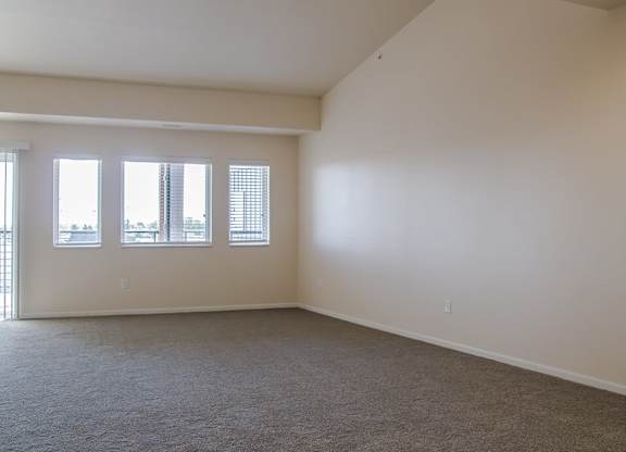 a bedroom with three windows and a carpeted floor
