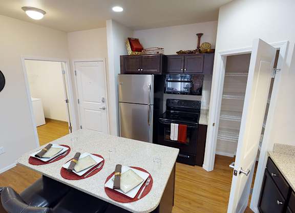 a kitchen with a table and chairs and a stainless steel refrigerator