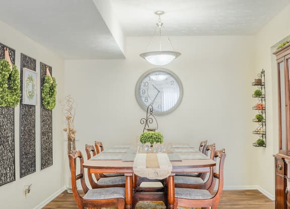 a dining room with a table and chairs and a large clock on the wall