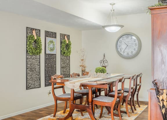 a dining room with a table and chairs and a clock on the wall