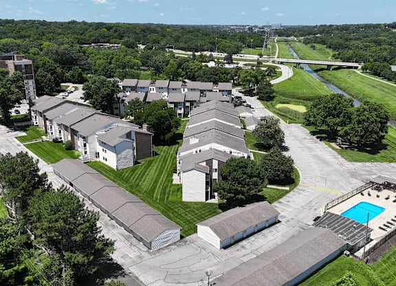 A bird's eye view of a residential area with houses, a pool, and a bridge.