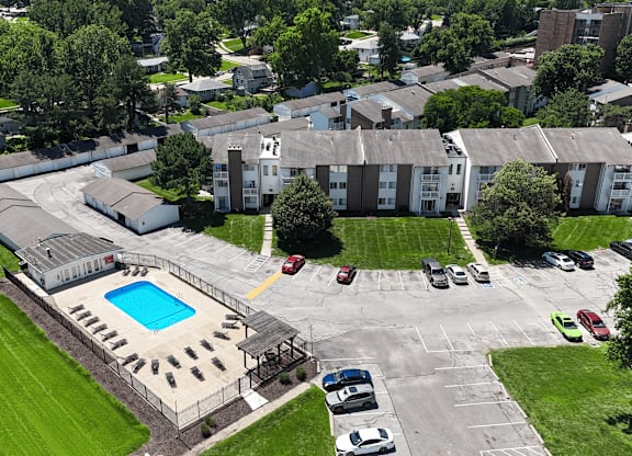 A large building complex with a pool in the middle of a parking lot.
